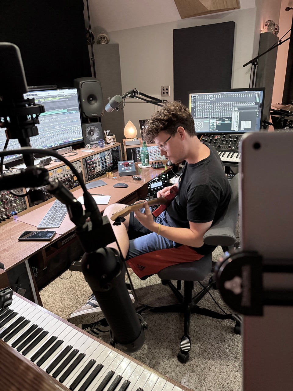 Guitarist working at the Sweetflow Studio recording desk surrounded by microphones, monitors, and outboard equipment